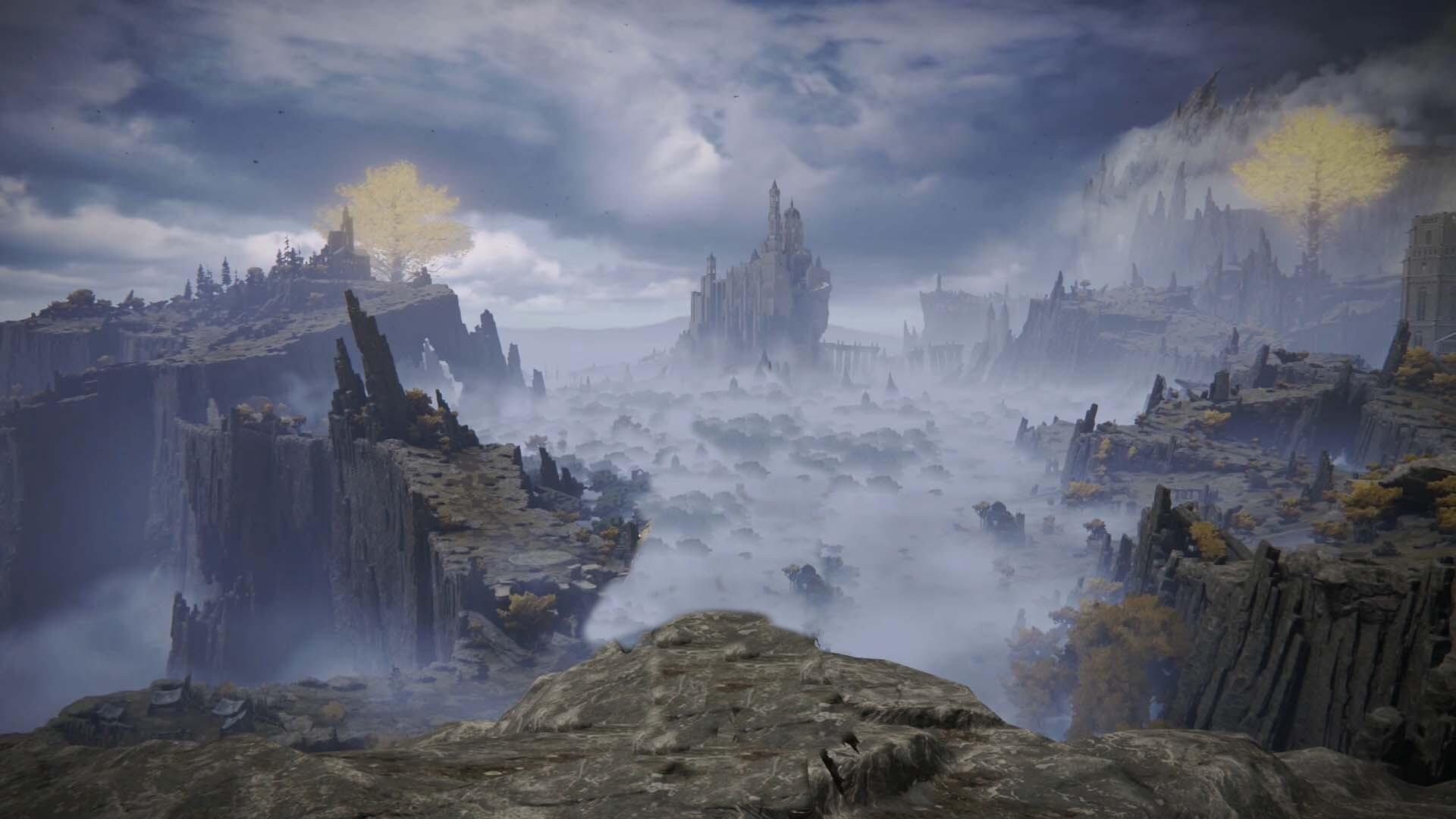 Screenshot of Elden Ring. It's taken from the top of a cliff, showing a beautiful landscape. To the left, many rocky mountains and a golden tree. To the center, a huge lake covered in mist, and a castle sitting on top of a cliff farther back. To the right, more rocky cliffs with trees and another golden tree.